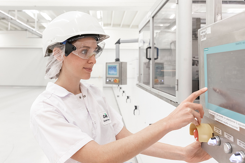 A female employee in safety gear working in a lab