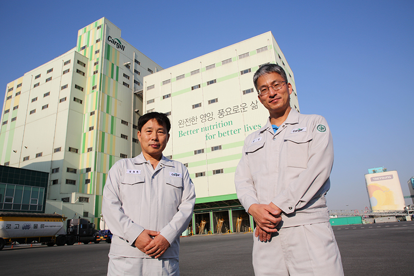 Hai người đàn ông đang tạo dáng chụp ảnh gần một nhà máy