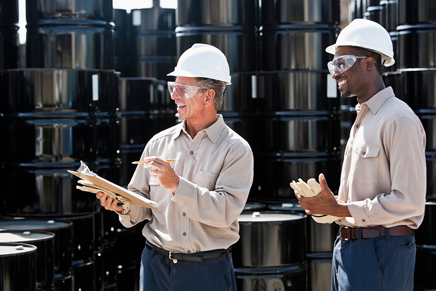 Hai nhân viên nam trò chuyện trước thùng kim loại