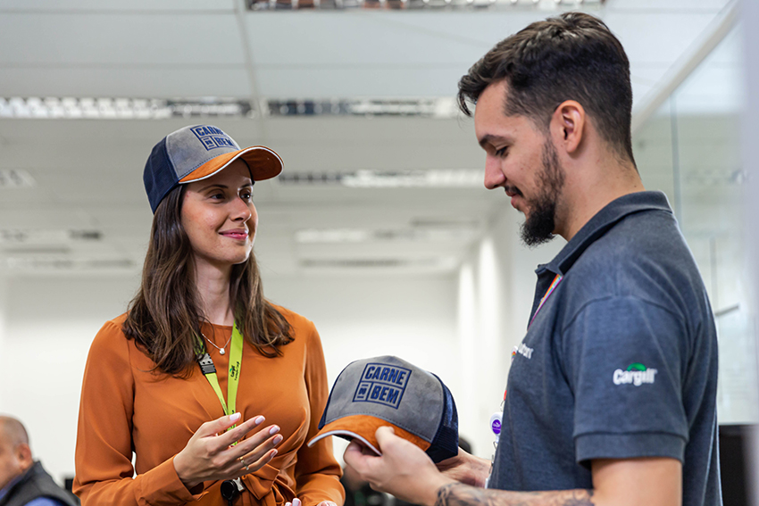 Một nhân viên nam nhận mũ bóng chày từ một nhân viên nữ